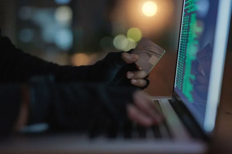 Shot of an unrecognisable hacker using a laptop to hack into a credit account