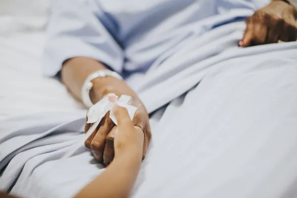 Daughter holding her mothers hand in the hospital, freepik