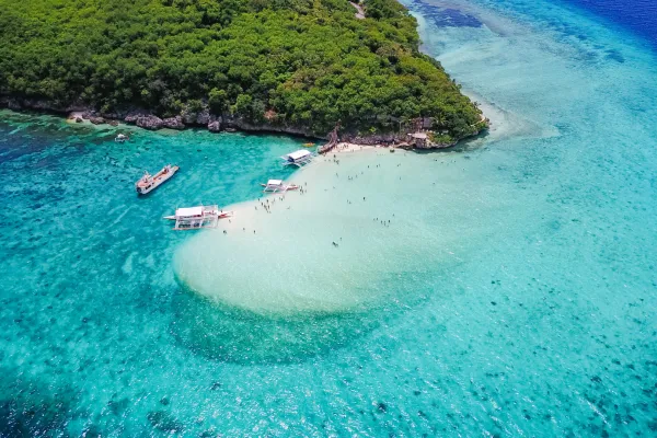 Aerial view of sandy beach with tourists swimming in beautiful clear sea water of the Sumilon island beach landing near Oslob, Cebu, Philippines. - Boost up color Processing.