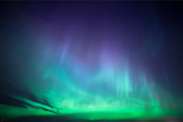 Severni sij, znan tudi kot aurora borealis, je pojav, ki se pojavlja v bližini Zemljinih polov, nastane pa, ko magnetno polje planeta usmeri nabite delce Sonca v ozračje. Foto: Canva
