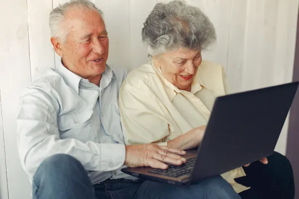 Grandparents at home. Old people use the laptop. Senior in a blue shirt.